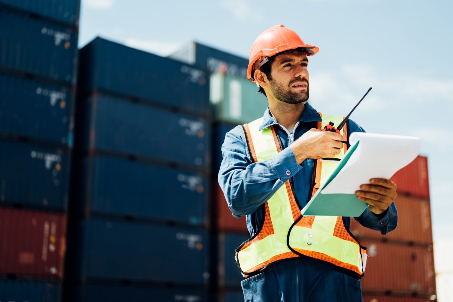 Industrial worker with walkie-talkie checking in cargo freight ship