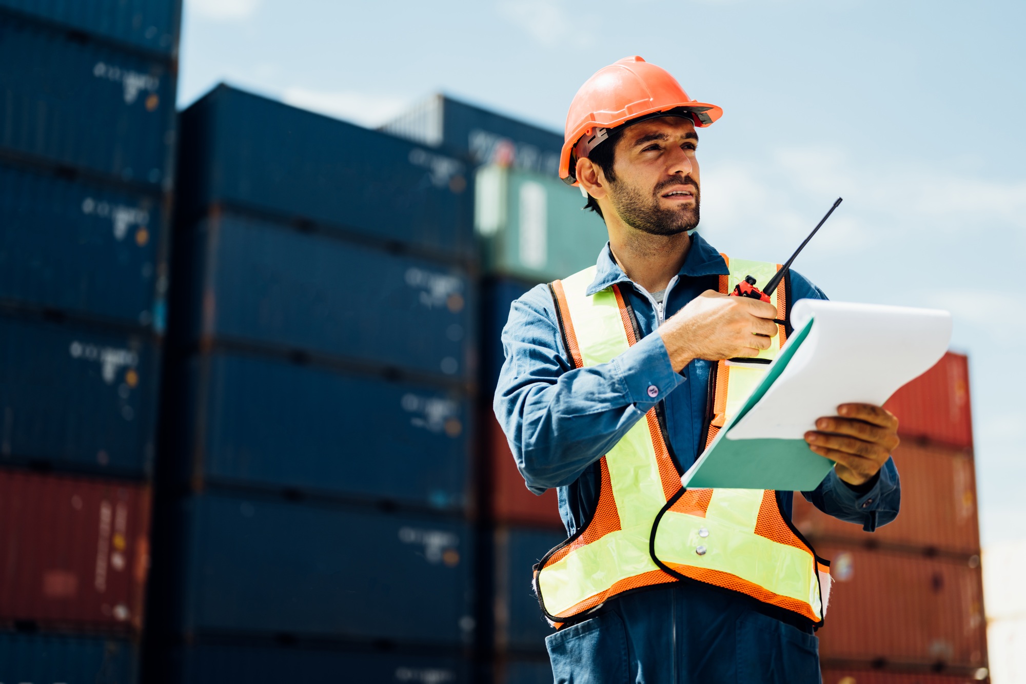 Industrial worker with walkie-talkie checking in cargo freight ship